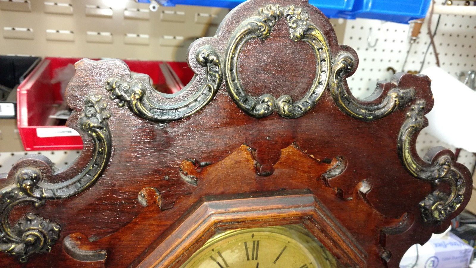 The carved wooden crest of an antique clock case during restoration work