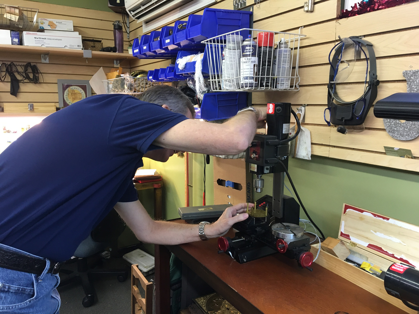 At the Gesswein's bench: working the bushing machine, with a National Watch & Clock guild plaque on the shop wall