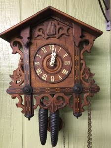 Restored Black Forest cuckoo clock with carved leaves and hanging pinecone weights