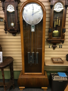 1930 Kienzle grandfather clock with a round silver dial in a light rounded-top case