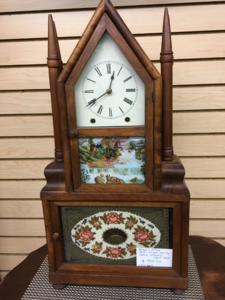 Restored steeple clock with pointed finials and a reverse-painted glass panel