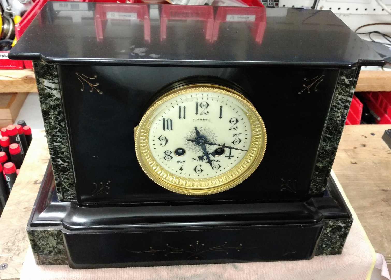 A restored black slate mantel clock with columns and a gilt dial